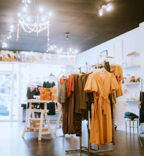 Clothing boutique with racks of colorful dresses and outfits neatly displayed under soft lighting, evoking the charm of a bed and breakfast near Torch Lake, with accessories and decor items arranged throughout the bright, inviting space.